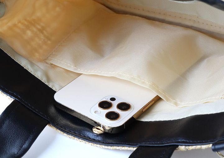 バッグ内側の内ポケットに白いスマートフォンを収納している様子
