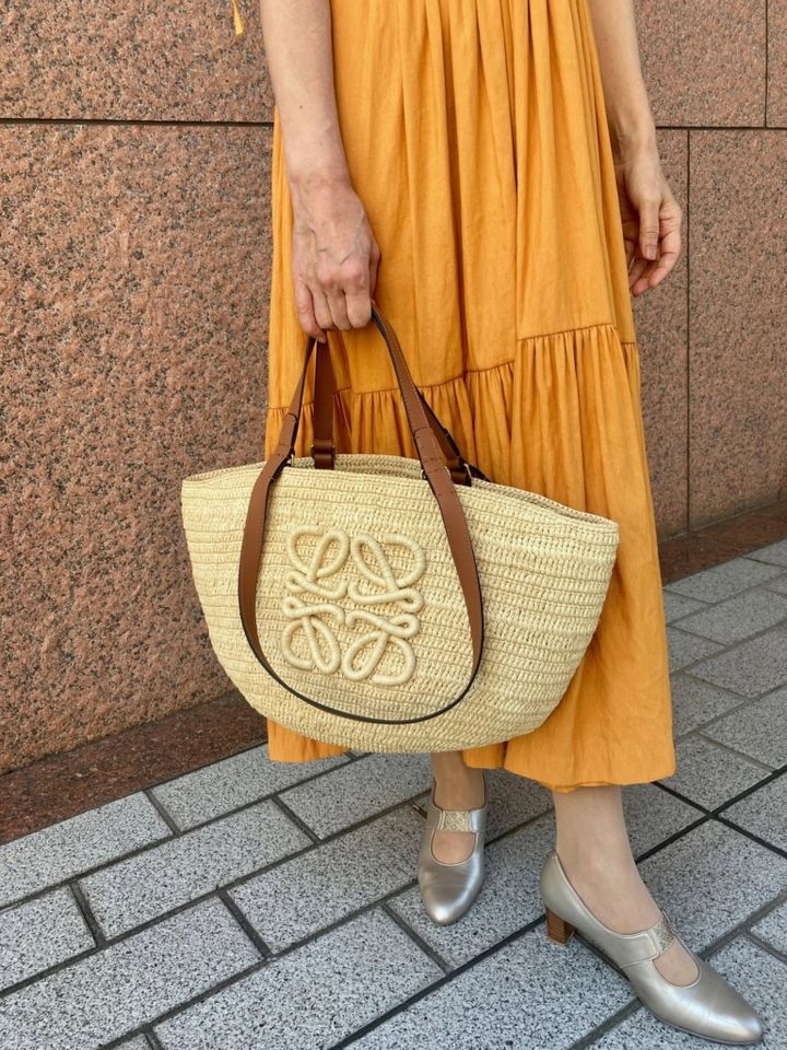 「鮮やかなオレンジワンピースには夏らしいカゴバッグが最適だと思い、アナグラムが端正に編み込まれたカゴバッグをチョイス。上品な佇まいなので、きちんと感もキープできます」