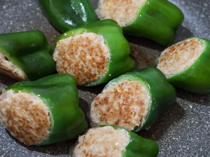 フライパンでこんがりと焼き色がついたピーマンの肉詰め