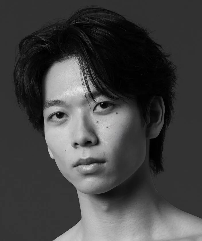 若い男性ダンサーの白黒プロフィール写真。上半身裸でグレー背景、K-BALLET TOKYOの出演者と思われる端正な顔立ちのポートレート