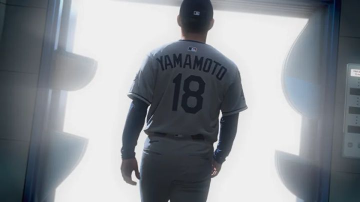 背番号18・YAMAMOTO表記のドジャースアウェイユニフォーム姿の山本由伸投手が、光溢れるエレベーターの扉へ向かって歩く後ろ姿のCMワンシーン