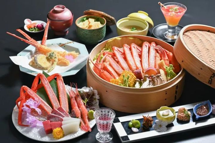 ズワイガニの蒸籠蒸し・カニ刺し・天ぷら・小鉢など複数料理を黒背景に並べた旅館カニ会席フルコースの全品俯瞰ショット