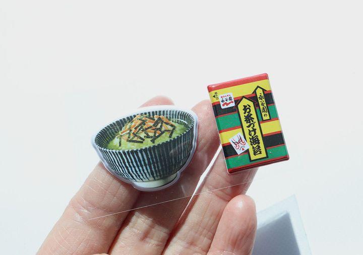 お茶碗とお茶づけ海苔小袋モチーフのぷっくりシール2点を手のひらに乗せた様子