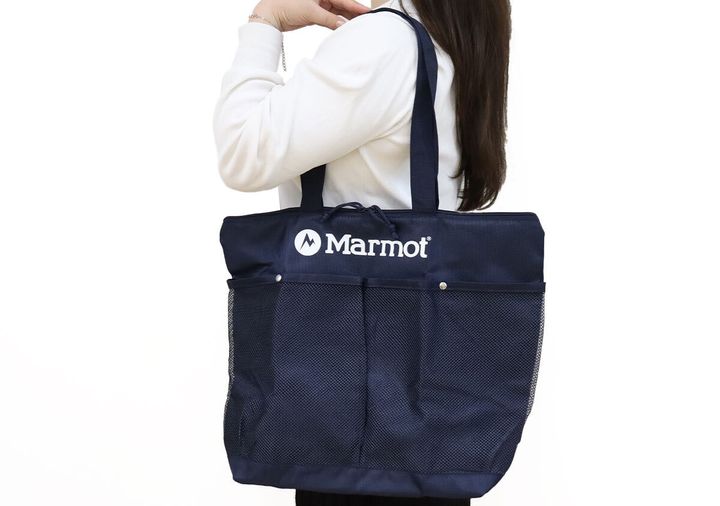 白いトップスの女性が紺色のMarmotBIGトートバッグを肩にかけている様子