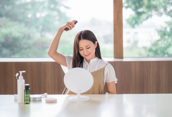 頭に日焼け止めスプレーをかける女性 イメージ
