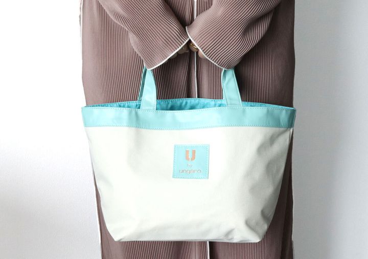 グレージュのリブニットセットアップの女性が舟形トートバッグを両手で前に持っている着用イメージ
