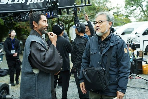 撮影の合間に黒沢監督と言葉を交わす本木雅弘さん。和やかな表情に黒沢組ならではの結束力がにじむ