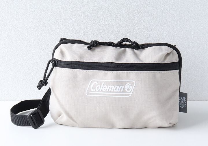 Colemanロゴ入りベージュの長方形ミニショルダーバッグ正面写真。ドローコードとフロントジッパーポケット付き