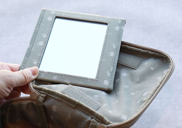 snow peakバニティポーチの蓋からキャンプ柄のミラーをマジックテープで取り外している手元