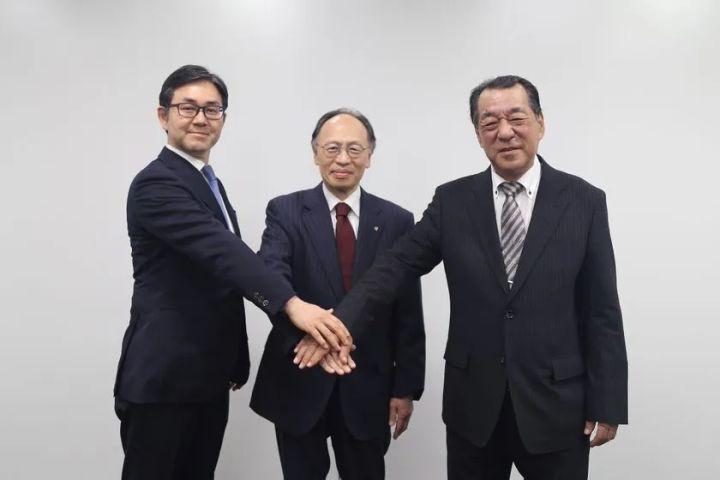 ミツバ・東洋電機製造・泰平電機の3社代表者がスーツ姿で中央に手を重ね合わせ、次世代電気式ドアシステム共同開発契約締結を示す握手写真