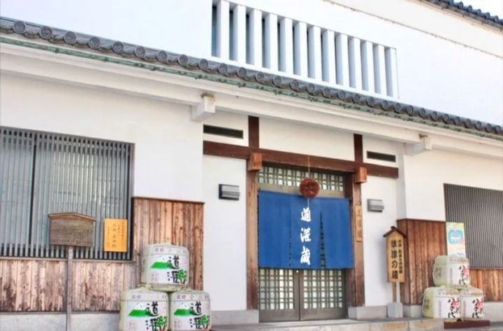 道灌蔵と書かれた暖簾が掛かる白壁の酒蔵正面玄関で、入口両脇に道灌銘柄の菰樽が積まれた外観写真