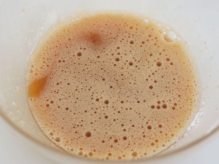 ガラスボウルに卵を割りほぐし砂糖を加えて泡立て器で混ぜ合わせた液体の俯瞰写真