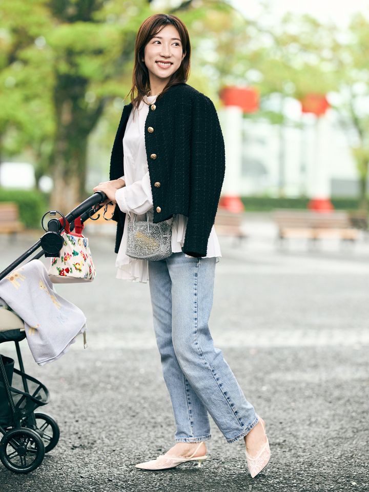 白ブラウスにデニムパンツ、黒いジャケットを肩に羽織ったコーディネート