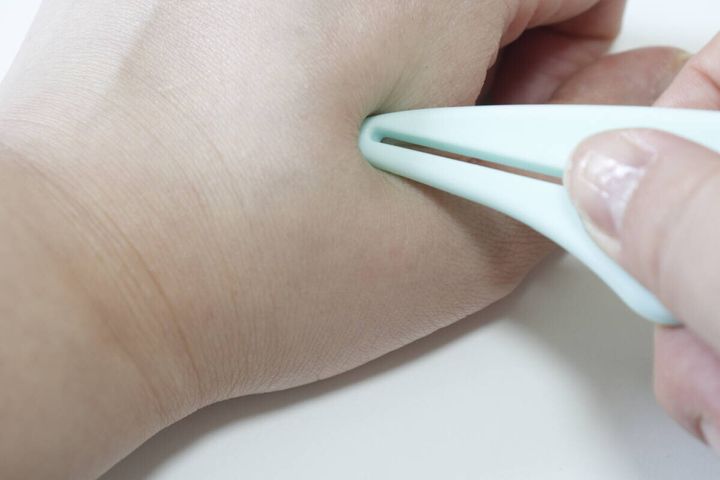 ダイソーのチェーン付きかっさで手のツボを押す様子