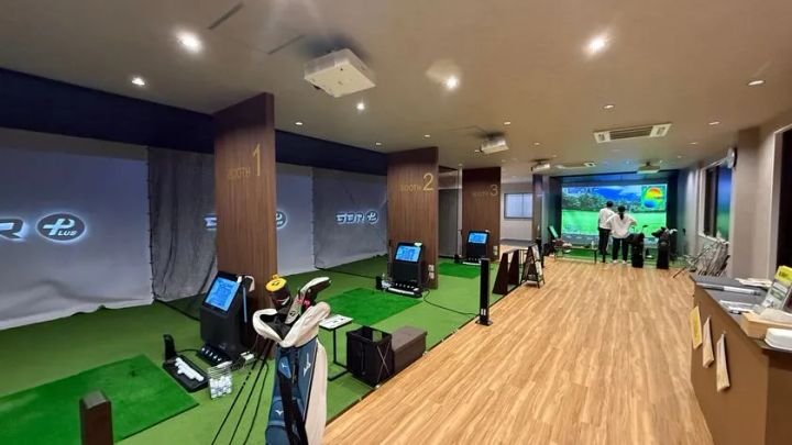 マイゴル小山店の室内シミュレーションゴルフブース3台の内装。BOOTH1〜3が並び、GOLFZONのシミュレーター機器・クラブスタンド・打席マットが設置され、利用者が練習している様子が写る