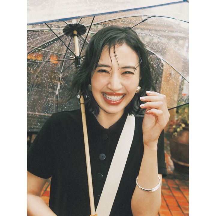 ポロカットソーを着てサードマガジンの傘を差した岡本あずささん