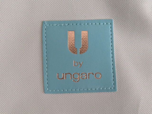 U by ungaroトートバッグのブランドロゴタグのアップ。ミントグリーンの台座にゴールドの「U by ungaro」の文字が入っている