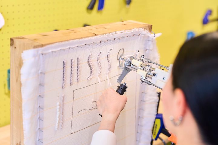 スタッフさんが書いた練習用のラインに沿って毛糸を打ち込む