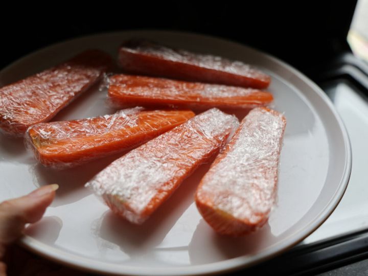 白い皿に縦半分に切ってラップでぴったり包んだにんじん6本を並べている写真