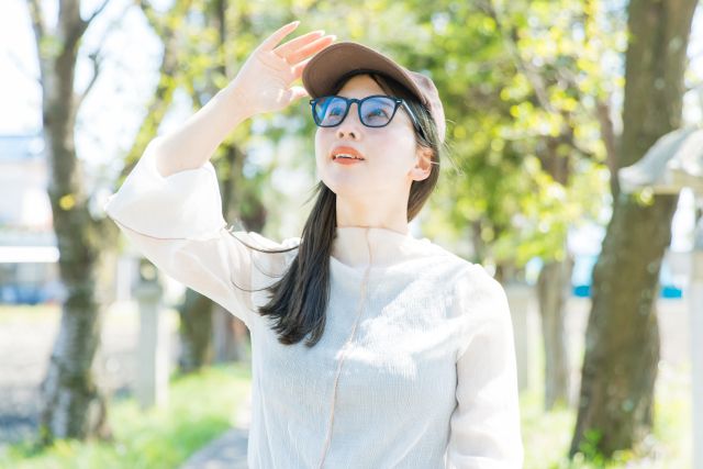 紫外線対策 サングラスと帽子をして外に出る女性