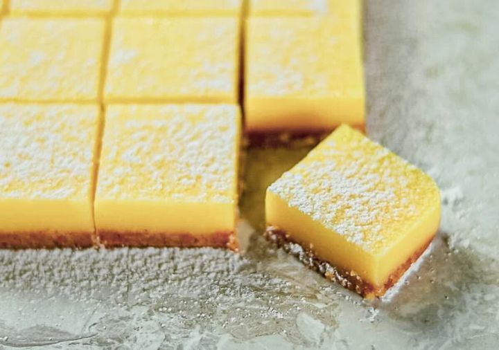 粉砂糖をふったスクエア型の黄色いレモンクリームのお菓子が、大理石風のテーブルに並べられた完成写真