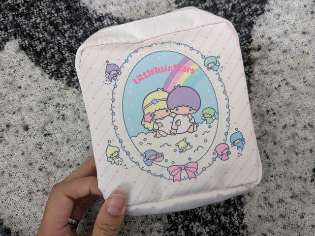 キキとララのファンシーポーチ正面。虹の上でキキとララが並ぶイラストと妖精さんたちのデザイン