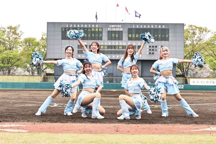 BCリーグオールスターゲーム開催予定の埼玉県営大宮公園野球場のスコアボード前で、水色ユニフォームのチアリーダー7名がポンポンを持ちポーズをとる集合写真