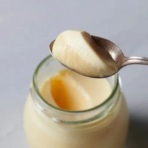 ガラス瓶に入ったアイスクリームをスプーンですくった近接ショット。アイスの乳白色とクリーミーなテクスチャ、瓶底のきな粉ソースが確認できる