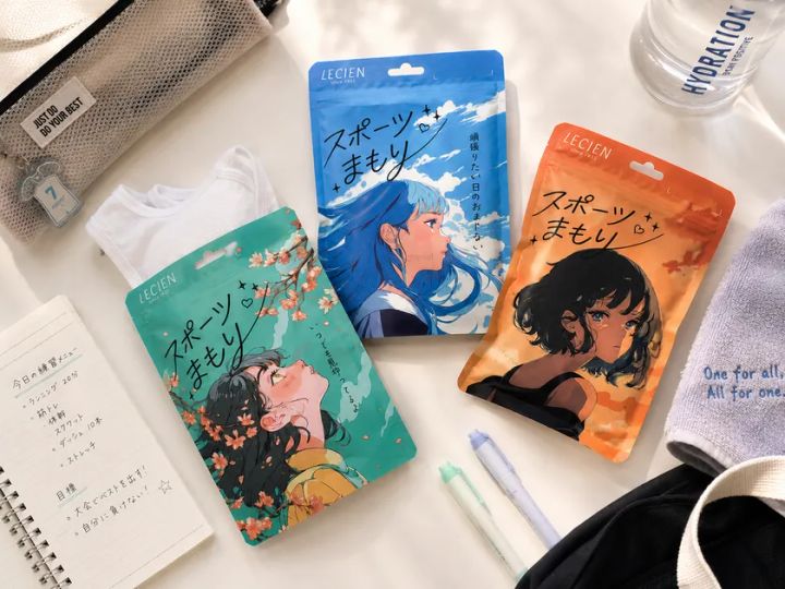 LECIEN「スポーツまもり」グリーン・ブルー・オレンジの3色バリエーションパッケージを、練習メニューノート・ウォーターボトル・スニーカー等の部活用品と並べて俯瞰撮影した商品ラインナップ写真