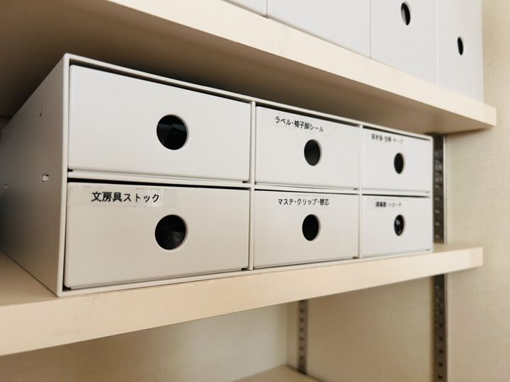 白い引き出し式収納ボックスに「文房具ストック」「ラベル・椅子脚シール」などのラベルを貼って中身を分かるようにした収納