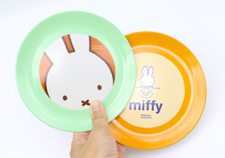 ミッフィーの顔がアップで描かれた緑のお皿を手で持ち上げ、下にミッフィーとmiffyロゴ入りのオレンジのお皿が置かれているメラミン樹脂プレート2枚
