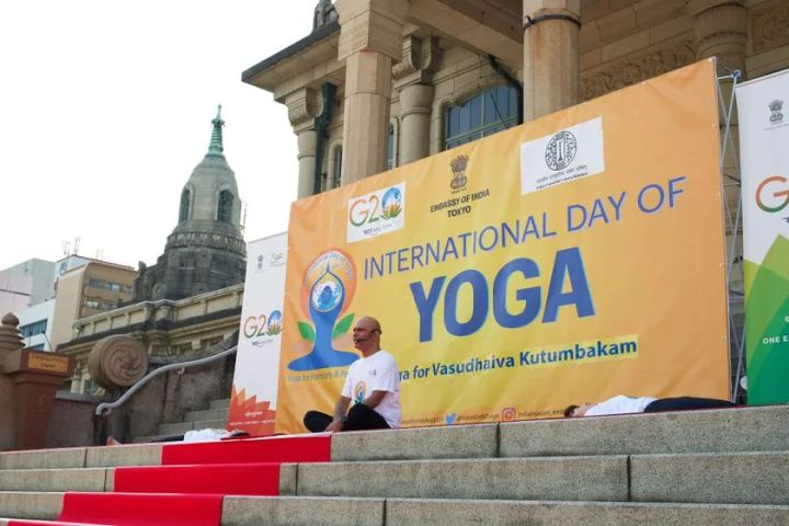 築地本願寺の階段前に設置されたEMBASSY OF INDIA TOKYO主催のInternational Day of Yoga黄色大型横断幕とG20ロゴ、インストラクターがポーズを取る様子