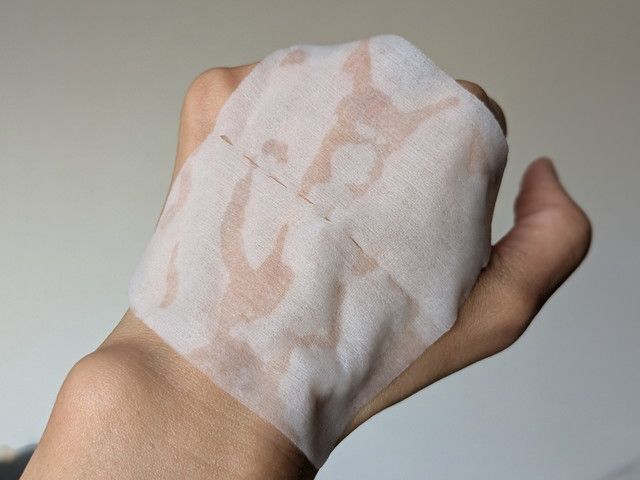 Wonjungyo モイストアップレディスキンパックのシートを手の甲にのせた様子。エッセンスがたっぷり含まれた白いシート