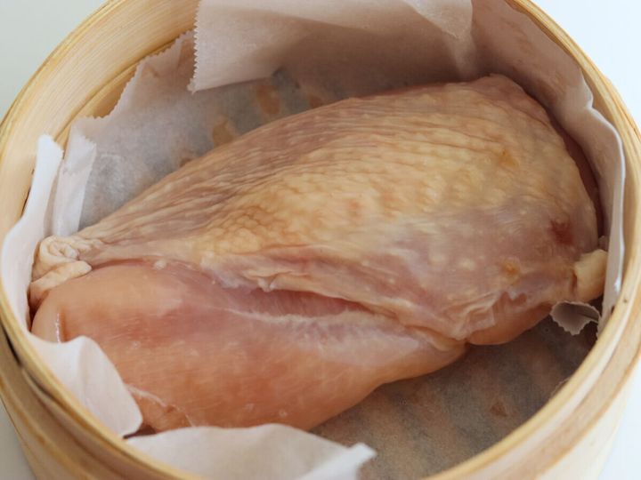 木製のせいろにクッキングシートを敷き皮を上にして鶏むね肉を入れた工程写真