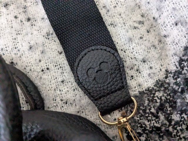 ショルダーストラップの付け根部分のアップ。ブラックのレザー調にミッキーシルエットがエンボス加工されている