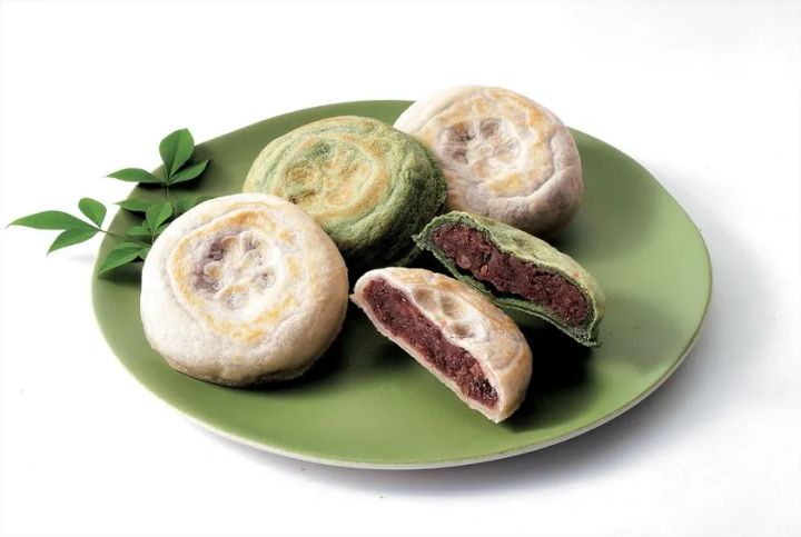 緑の皿に並んだ焼き菓子（白皮・抹茶皮）3個と、断面を見せた抹茶皮の1個。あんこが詰まった饅頭系スイーツの商品写真