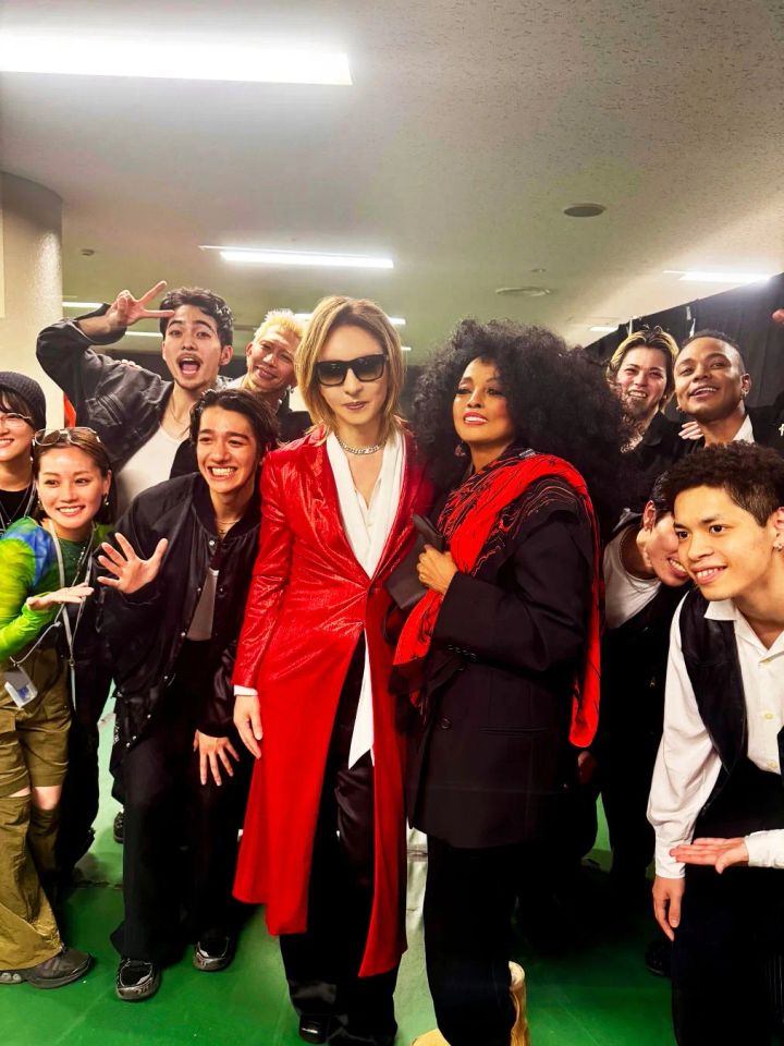 赤いロングコート姿のYOSHIKIとダイアナ・ロスがバックステージで出演スタッフ十数名と囲んで撮影した集合写真