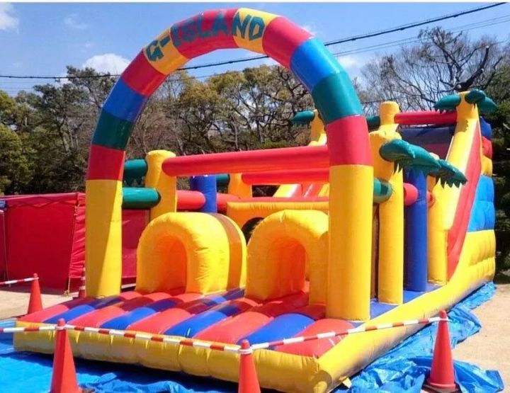 全肉祭の子ども向けアトラクションとして設置されたG-ISLANDロゴ入り大型エアー遊具。赤・黄・青のカラフルなトンネル付きアスレチック型バウンサー
