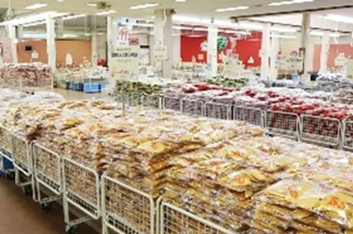 大型倉庫型店舗内に金属カゴ台車で山積みされた袋菓子・乾物類の陳列風景。知多半島の道の駅または土産物店の売り場全体を広角で撮影したショット