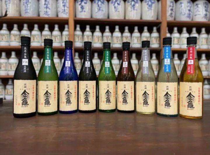 長寿金亀シリーズ9本の精米歩合別ラインナップ（F20〜赤）を酒蔵の甕棚前に並べた商品集合写真