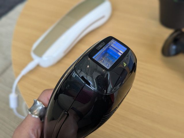 Ulike IPL光美容器のブラックモデルを手に持ったアップ。青く光るサファイア冷感ヘッドが見える