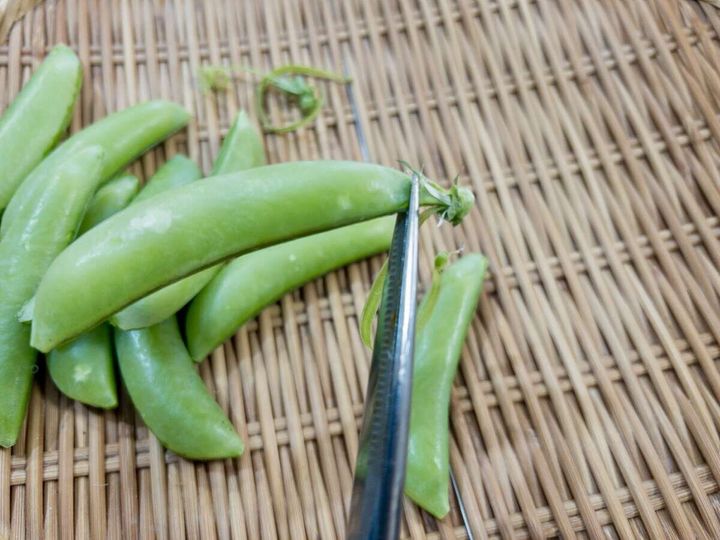 キッチンバサミでスナップエンドウのガクの筋を切り取っている手元の俯瞰写真