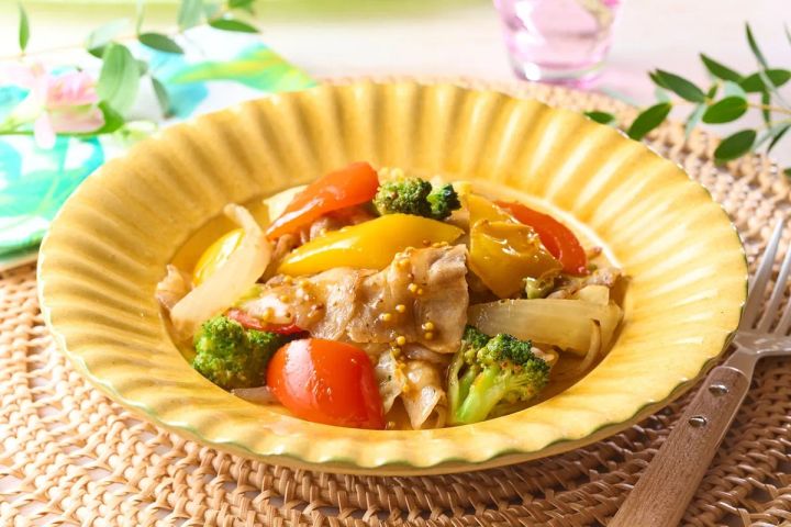 鶏肉・ブロッコリー・赤黄トマト・パプリカ・玉ねぎをマスタードソースで炒めた彩り野菜炒めの単品アップ。金色のリム皿に盛り付け