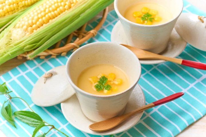 夏トウモロコシを使ったコーンポタージュスープを白い湯呑み型カップ2杯に注ぎ、トウモロコシの実とパセリをトッピングした料理写真