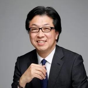 眼鏡をかけたスーツ姿の男性のプロフィール写真。グレー背景で笑顔、ATD-ICE 2026報告会の登壇者またはユームテクノロジー関係者の顔写真と思われる