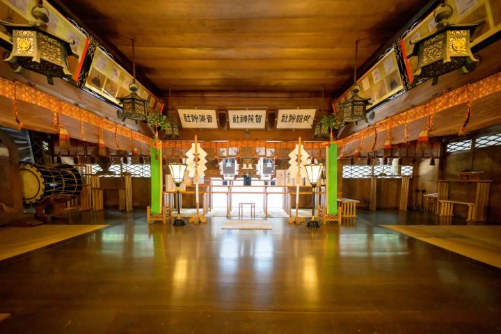 青海神社の拝殿内部を正面から撮影した写真で、御祖神社・賀茂神社・青滝神社の扁額、金属製の吊り灯籠、紙垂付き緑柱、太鼓が確認できる木造空間