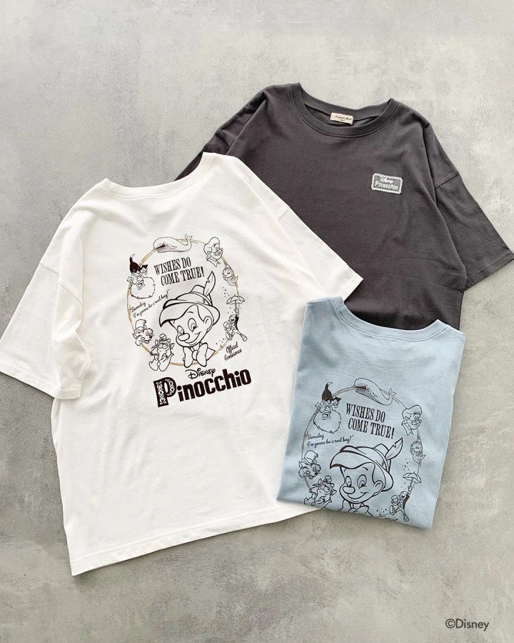 ピノキオと登場キャラクターを囲むサークルプリント入り半袖Tシャツ3色（ホワイト・チャコールグレー・ライトブルー）の表面デザインを示した商品ショット
