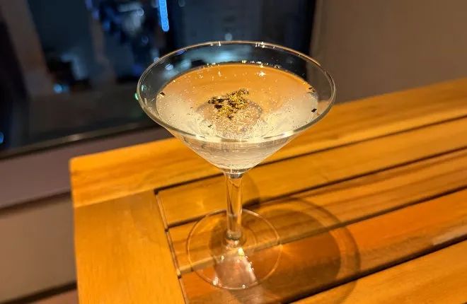 マティーニグラスに注がれた透明なカクテルの単品写真。液面に金箔がトッピングされており、20周年限定ドリンクメニューの仕様を示す接写ショット