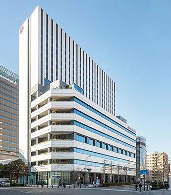 横浜東急REIホテルの外観全景写真。みなとみらいエリアに立つ白色の高層ビルで、上部に東急REIロゴが確認でき、低層部の青いガラスファサードと周辺の街路が写る。