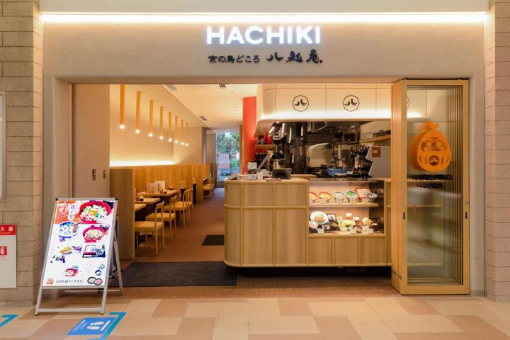 HACHIKI 八起庵の飲食店舗正面外観。店名看板・木調カウンター・食品サンプルケース・店内テーブル席・A看板（親子丼メニュー）が確認できる